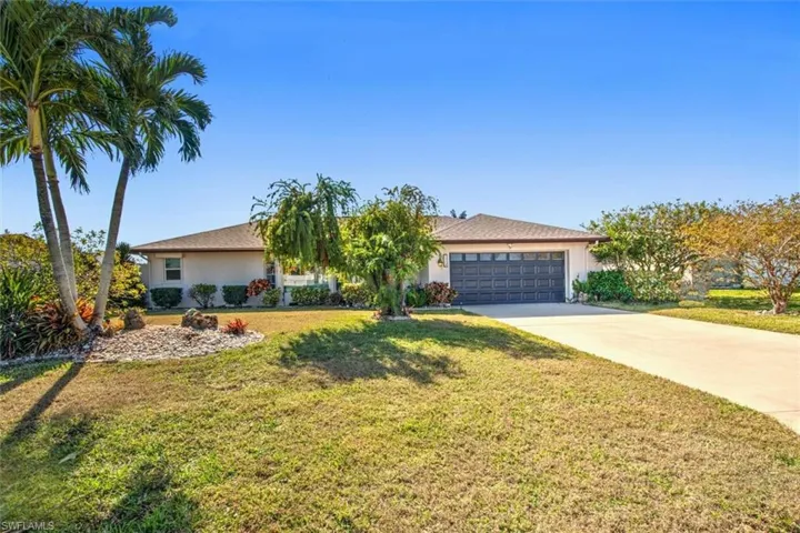 View of front of home with a front lawn, concrete driveway, a garage, and stucco siding
