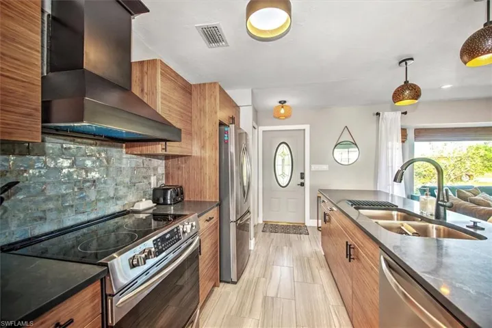 Kitchen with stainless steel appliances, dark stone counters, plenty of natural light, and wood finish cabinets