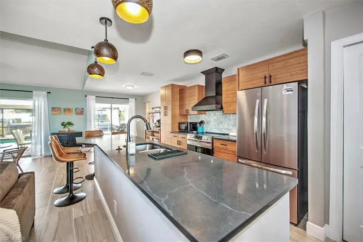 Kitchen featuring a breakfast bar area, stainless steel appliances, wood finish cabinets, a large island, and backsplash