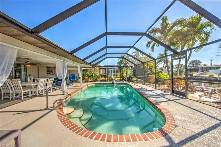 Swimming pool with outdoor dining area, glass enclosure, a sunroom, and a patio