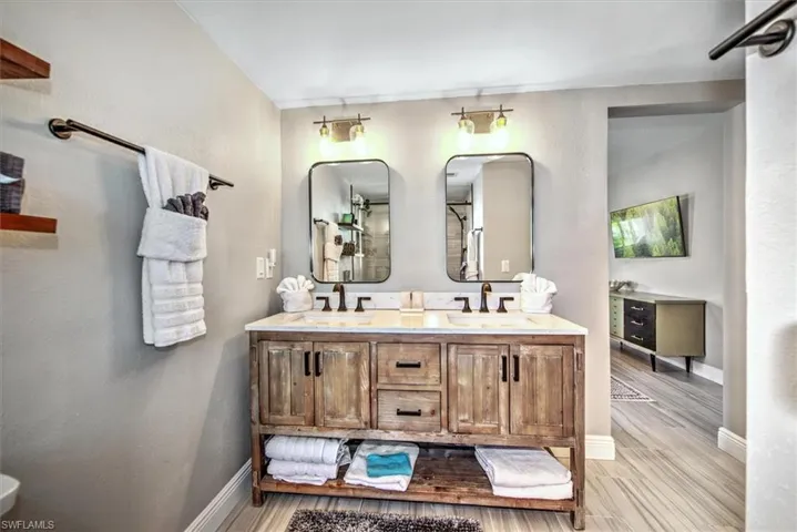 Full bathroom featuring double vanity, a textured wall, and light wood-type flooring