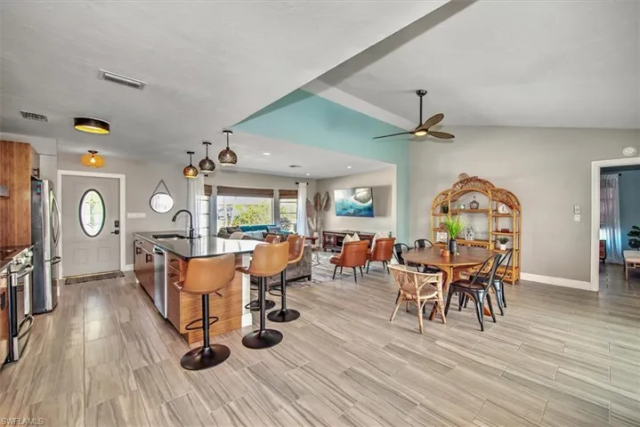 Kitchen featuring open floor plan, stainless steel appliances, a breakfast bar, an island with sink, and pendant lighting