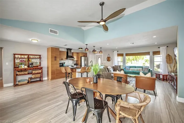 Dining room featuring a ceiling fan, vaulted ceiling, and wood tiled floors