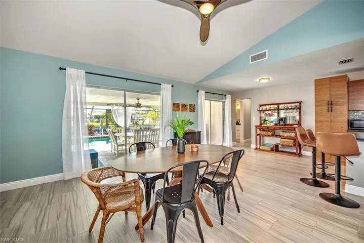 Dining room featuring ceiling fan, lofted ceiling, light wood-type flooring, and a sunroom