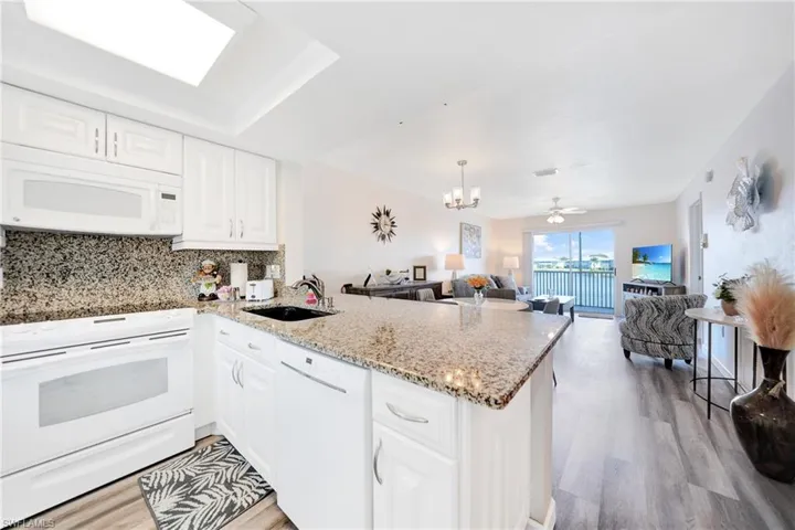 Kitchen featuring kitchen peninsula, light hardwood / wood-style flooring, white appliances, and ceiling fan with notable chandelier