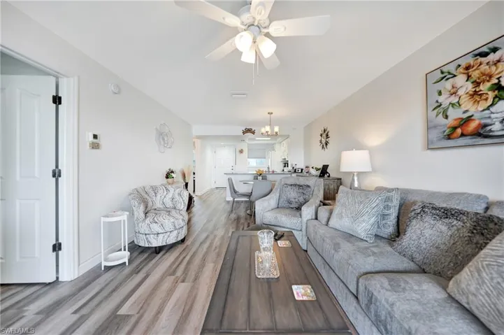 Living room with ceiling fan with notable chandelier and hardwood / wood-style floors