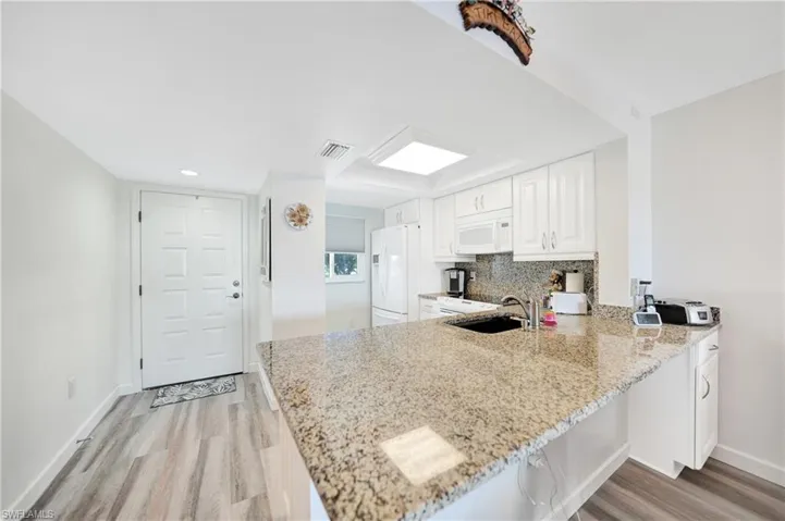 Kitchen featuring tasteful backsplash, white appliances, kitchen peninsula, and light hardwood / wood-style floors