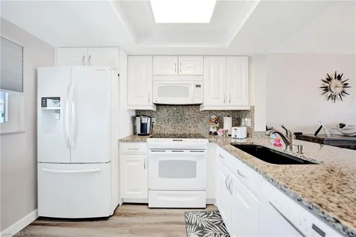 Kitchen featuring light wood-type flooring, white appliances, sink, and white cabinetry