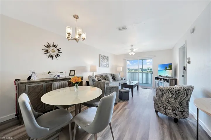 Dining space with wood-type flooring and ceiling fan with notable chandelier