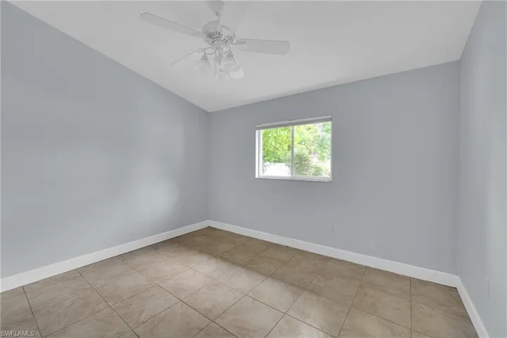 Tiled spare room with a ceiling fan and lofted ceiling
