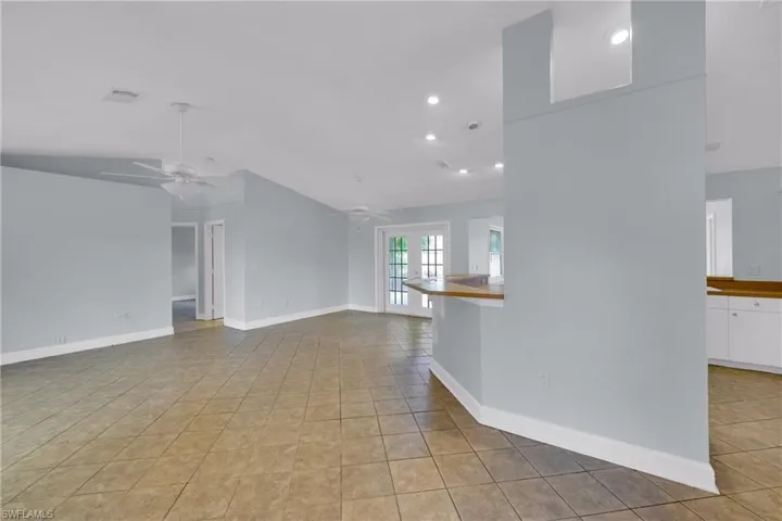 Unfurnished living room with ceiling fan, vaulted ceiling, french doors, light tile patterned floors, and recessed lighting