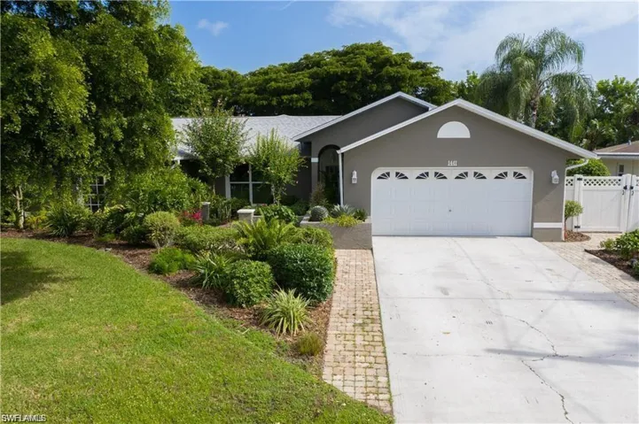 View of front of property with concrete driveway, stucco siding, fence, a front lawn, and a garage