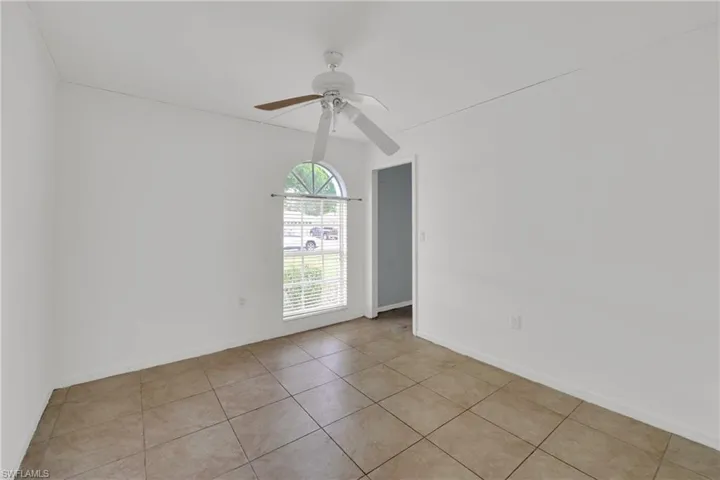 Empty room with a ceiling fan and light tile patterned floors