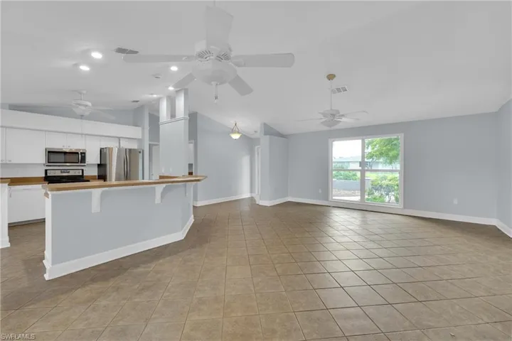 Unfurnished living room featuring lofted ceiling, light tile patterned floors, ceiling fan, and recessed lighting