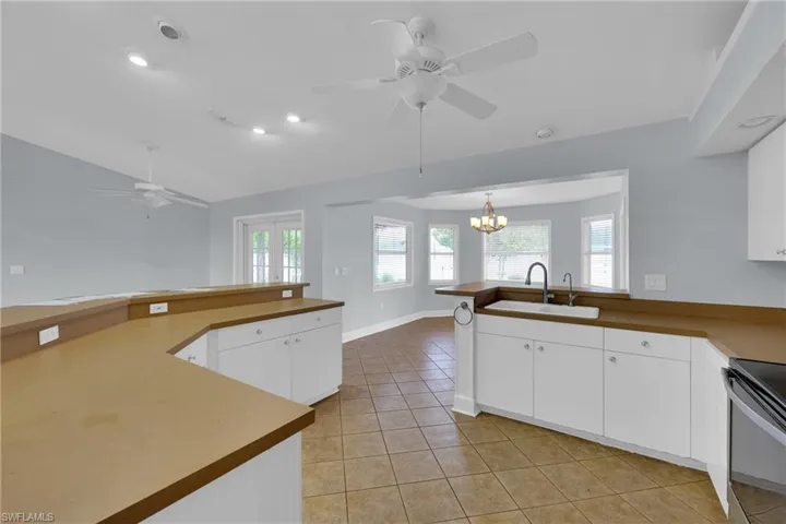 Kitchen with a ceiling fan, a chandelier, light tile patterned floors, a peninsula, and lofted ceiling