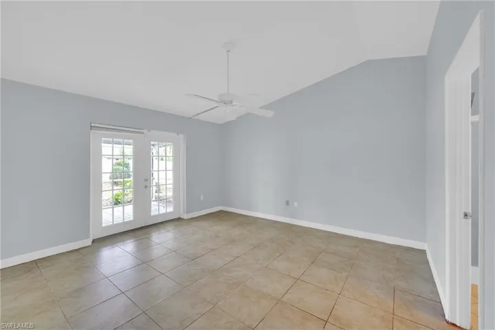 Spare room featuring lofted ceiling, light tile patterned flooring, ceiling fan, and french doors