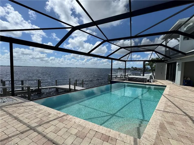 Outdoor pool with a boat dock, a water view, a patio, and a lanai