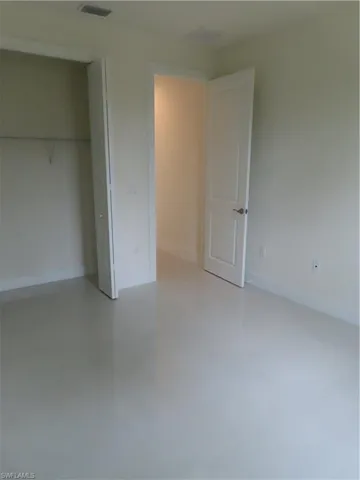 Unfurnished bedroom featuring concrete floors and a closet
