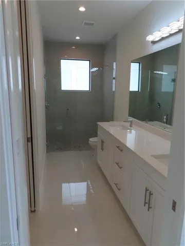 Full bath featuring a stall shower, tile patterned floors, double vanity, and recessed lighting