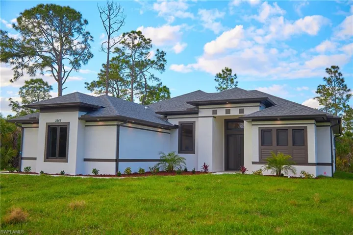 Prairie-style home with stucco siding, a front yard, and roof with shingles