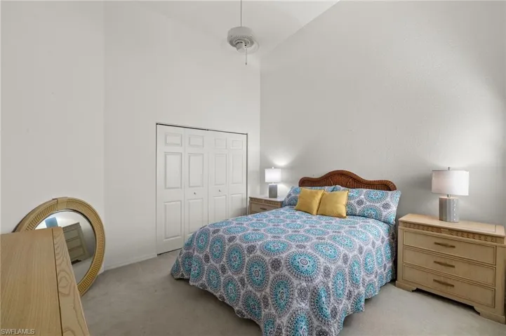 Carpeted bedroom featuring ceiling fan, a closet, and high vaulted ceiling