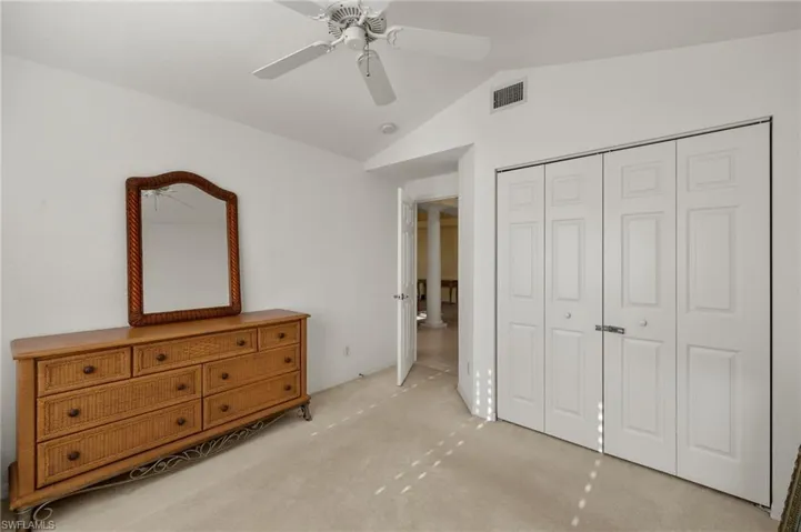 Bedroom featuring a closet, ceiling fan, lofted ceiling, and light colored carpet