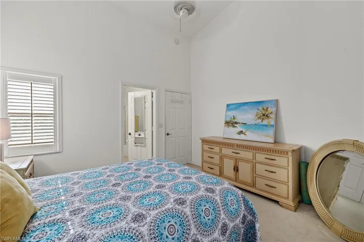 Bedroom featuring ceiling fan, light carpet, and high vaulted ceiling