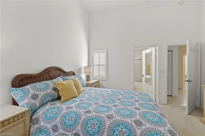 Bedroom with connected bathroom and high vaulted ceiling