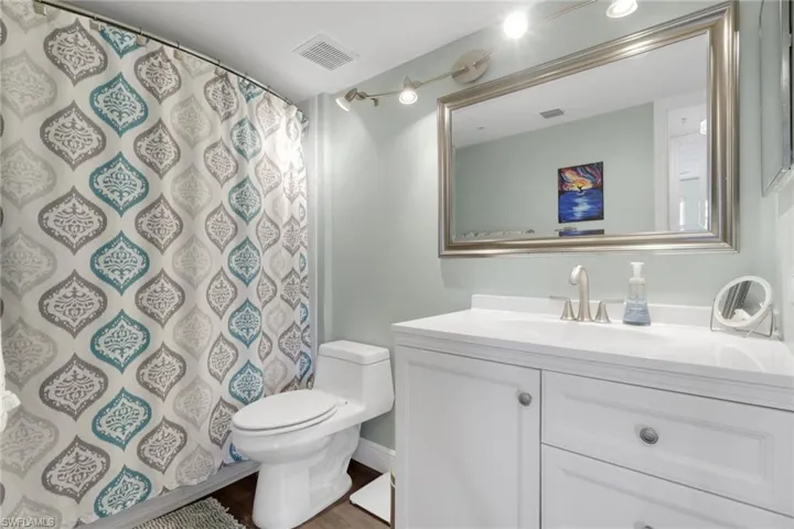 Full bath with vanity, a shower with shower curtain, and dark wood-style floors