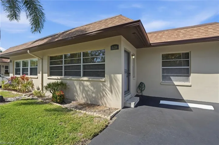 Doorway to property featuring a shingled roof, stucco siding, and a yard