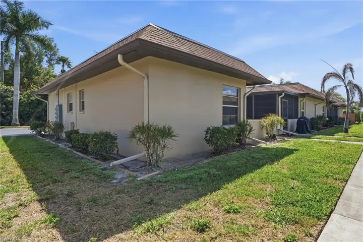 View of property exterior featuring a lawn and stucco siding
