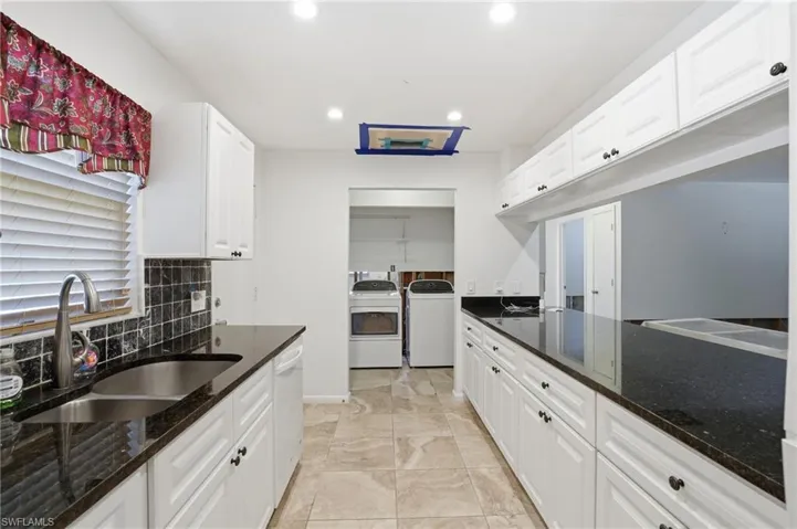Kitchen featuring dark stone counters, white cabinets, recessed lighting, dishwasher, and separate washer and dryer