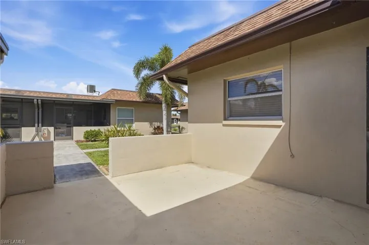 View of property exterior with stucco siding, a sunroom, and a patio area
