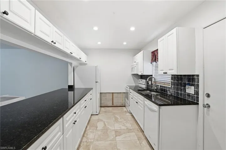 Kitchen with white cabinets, white appliances, dark stone countertops, recessed lighting, and decorative backsplash