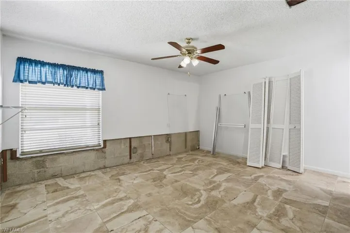 Empty room featuring ceiling fan and a textured ceiling