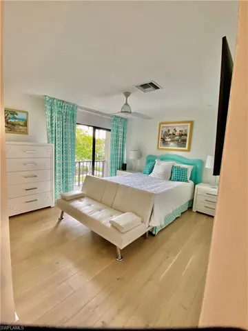 Bedroom featuring access to outside, wood finished floors, visible vents, and a ceiling fan