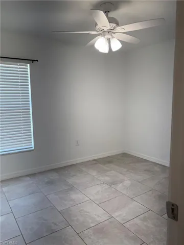 Spare room featuring a ceiling fan and baseboards