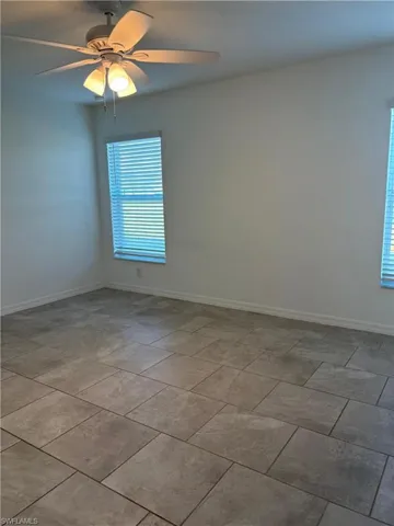 Empty room featuring a ceiling fan and baseboards