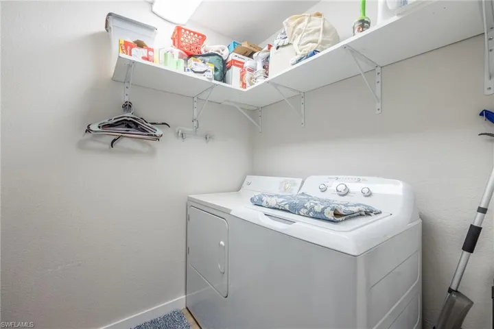 Laundry area featuring washing machine and clothes dryer and a textured wall