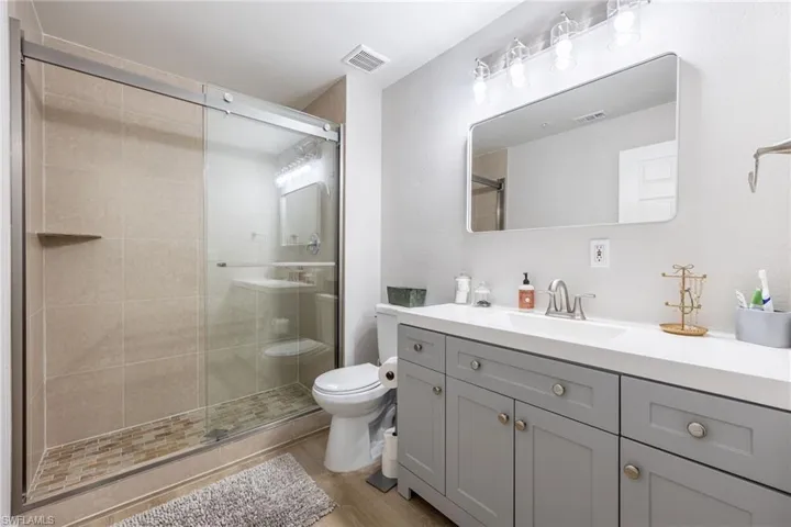 Bathroom with vanity, a stall shower, and light wood-style floors