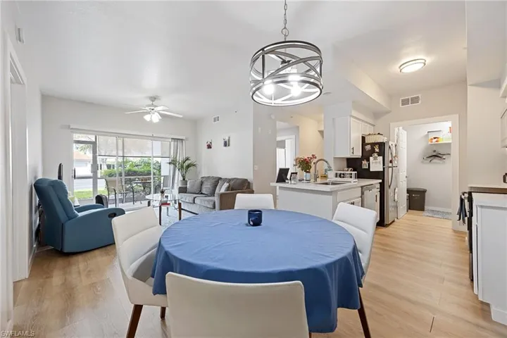 Dining area with light wood-type flooring, a chandelier, and a ceiling fan