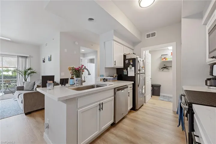 Kitchen with white cabinetry, light wood-style floors, open floor plan, stainless steel appliances, and a peninsula