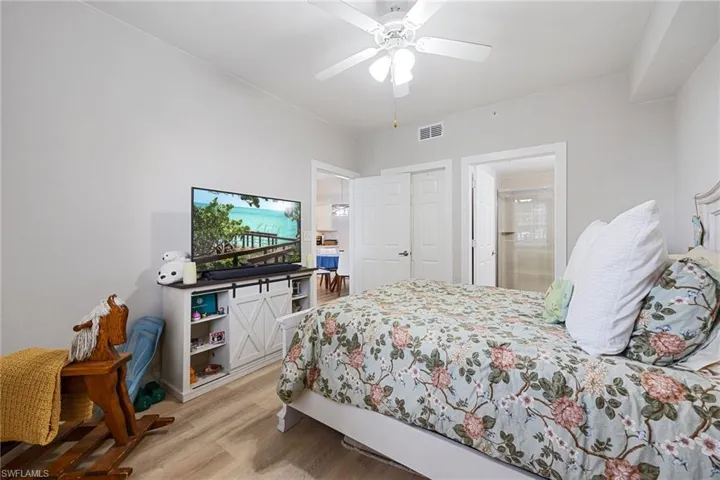 Bedroom with light wood-style floors, a closet, ceiling fan, and ensuite bathroom