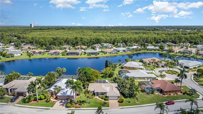 Aerial perspective of suburban area featuring a large body of water and a heavily wooded area
