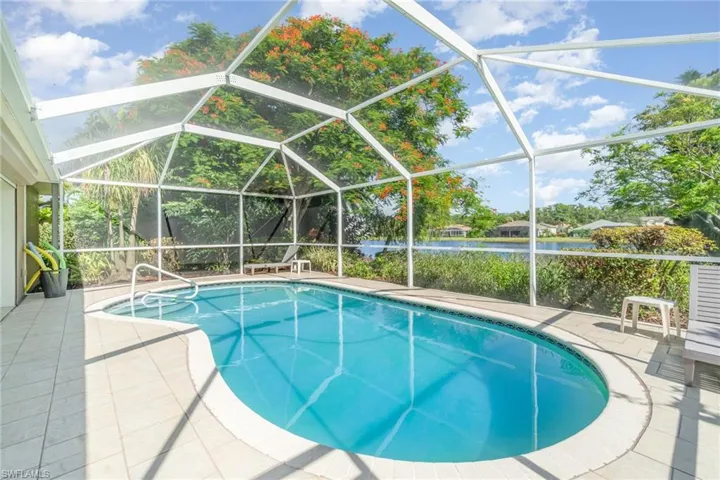 Outdoor pool with a water view, a sunroom, a lanai, and a patio
