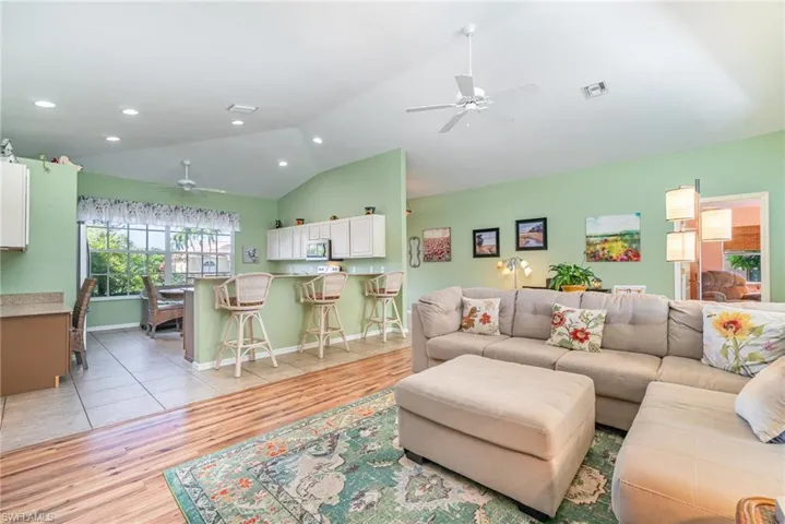 Living area with a ceiling fan, light wood-type flooring, lofted ceiling, and recessed lighting