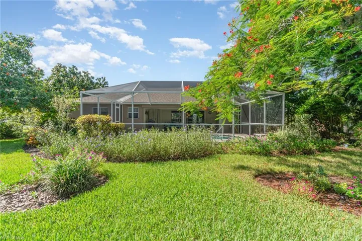 Back of house featuring a sunroom, glass enclosure, and a yard