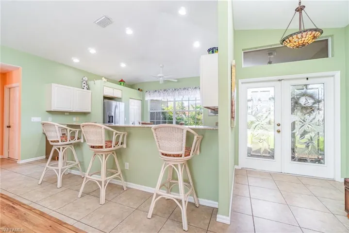 Kitchen with a kitchen breakfast bar, french doors, light tile patterned flooring, recessed lighting, and white cabinets