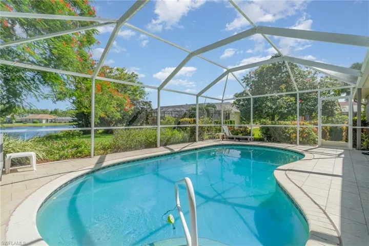 Outdoor pool with glass enclosure, a sunroom, and a patio