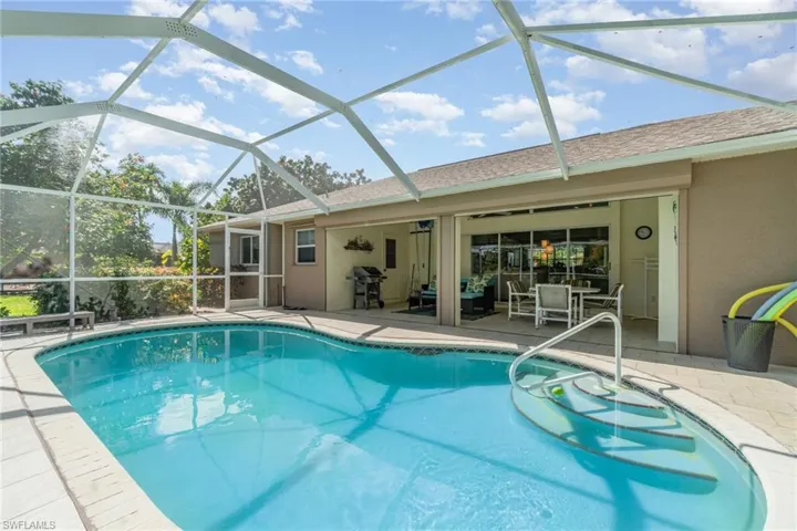 Outdoor pool featuring a sunroom, a patio area, grilling area, and glass enclosure
